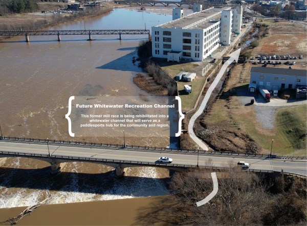 Aerial view of a river and adjacent buildings with a highlighted area labeled Future Whitewater Recreation Channel, showcasing redevelopment plans by a whitewater engineer for a paddlesports hub; bridges and roads cross the water.